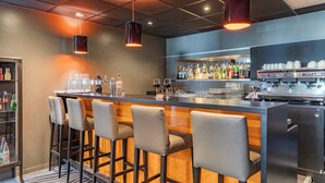 A bar area with a long counter, bar stools, and a variety of bottles and glasses. - Appart'City Confort Lyon Cité Internationale (Caluire-et-Cuire)