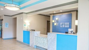 Ein Hotel-Empfangsbereich mit blau-weißer Farbgebung, einer Rezeption und einem an der Wand befestigten Schild für Holiday Inn Express.