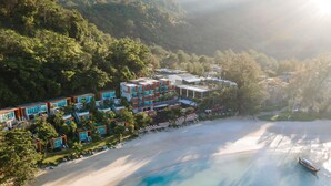 Un hotel frente al mar con varias construcciones, una playa y aguas azules cristalinas.