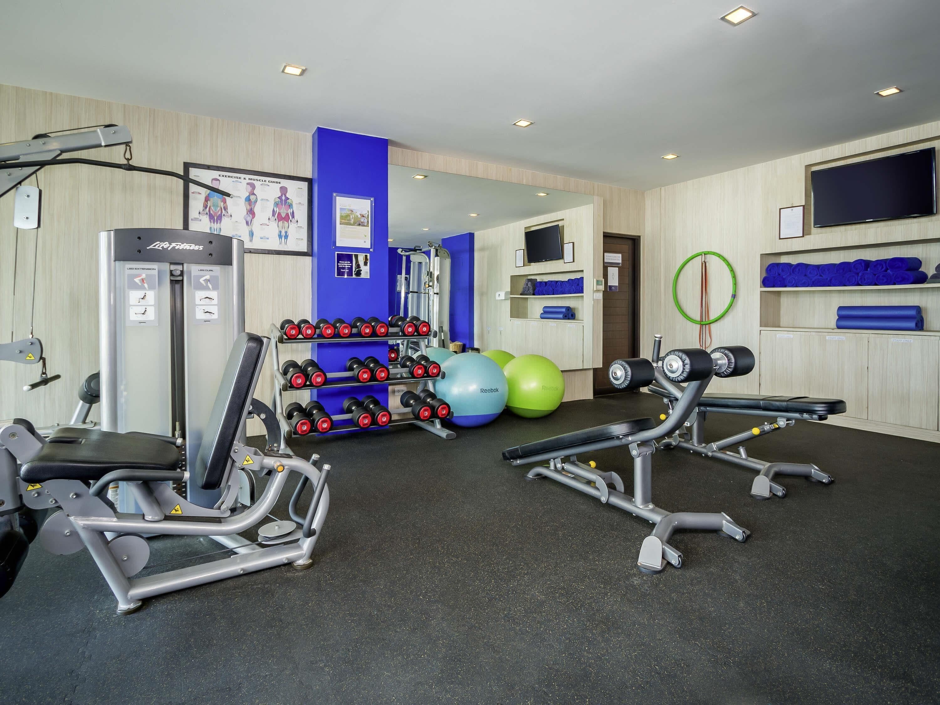 Une salle de sport équipée de matériel d’exercice, d’haltères et de ballons de gymnastique.