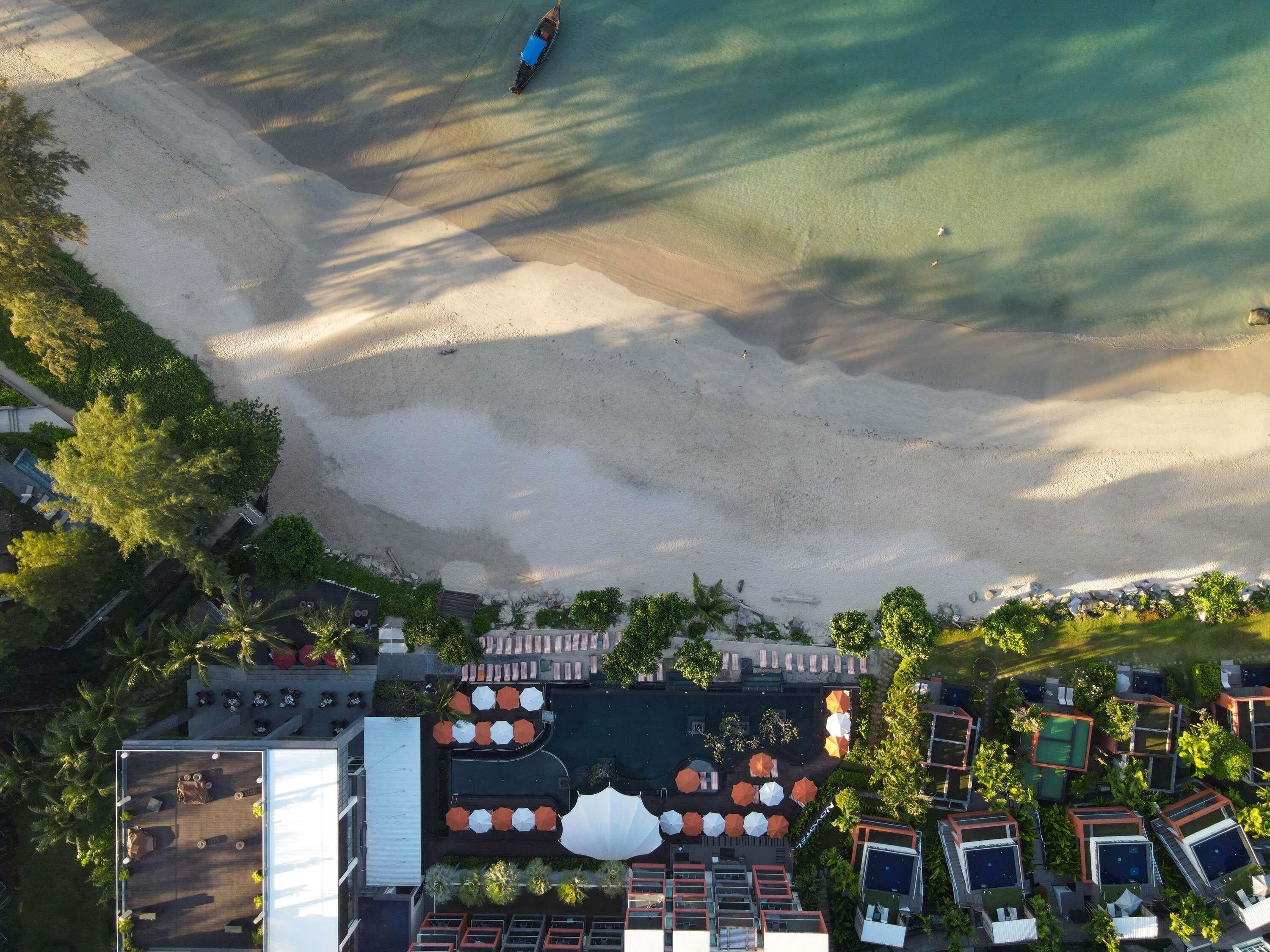 An aerial view of a resort with a beach, pool area, and multiple buildings.