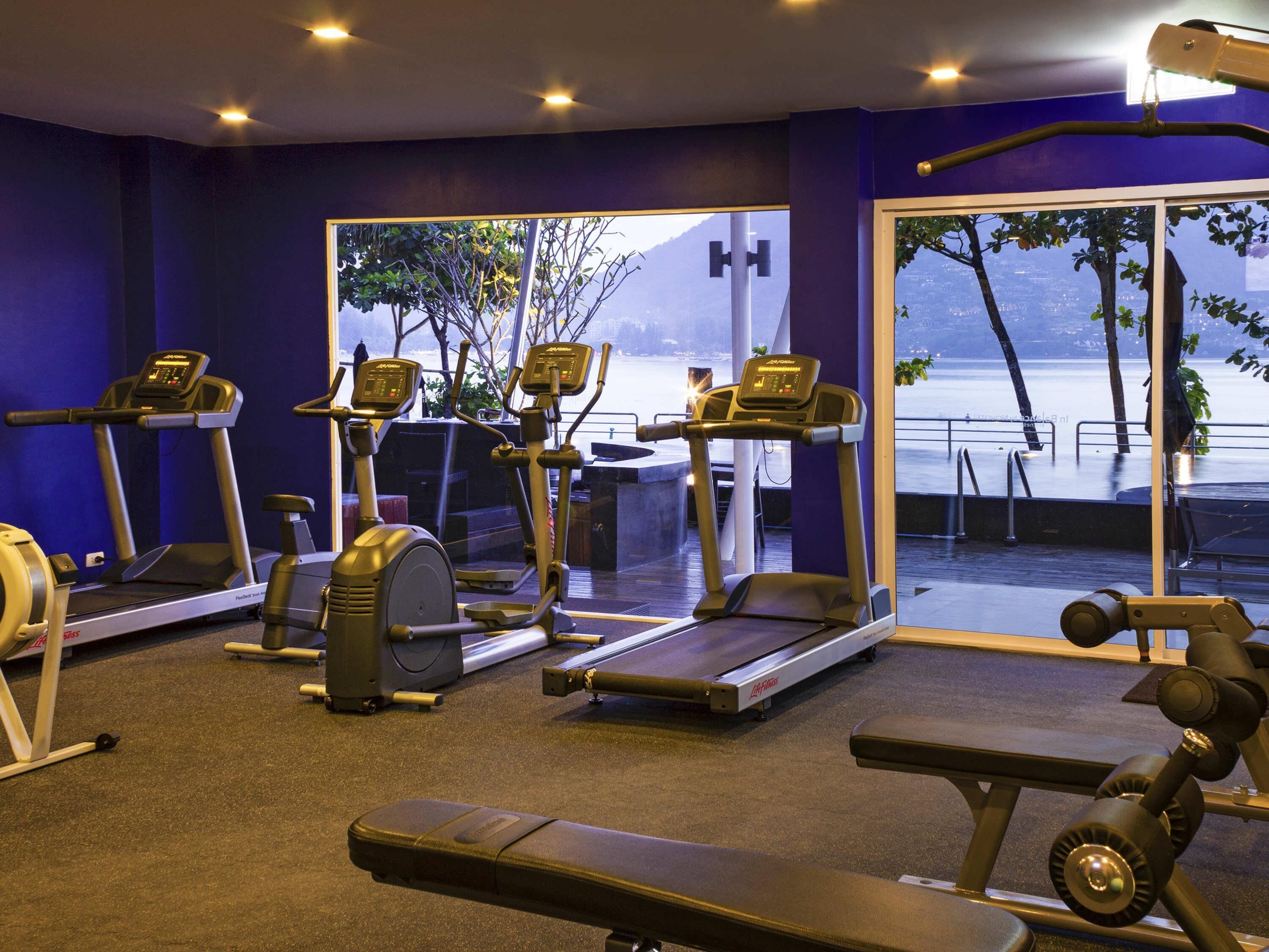 A gym with treadmills, elliptical machines, and a bench.