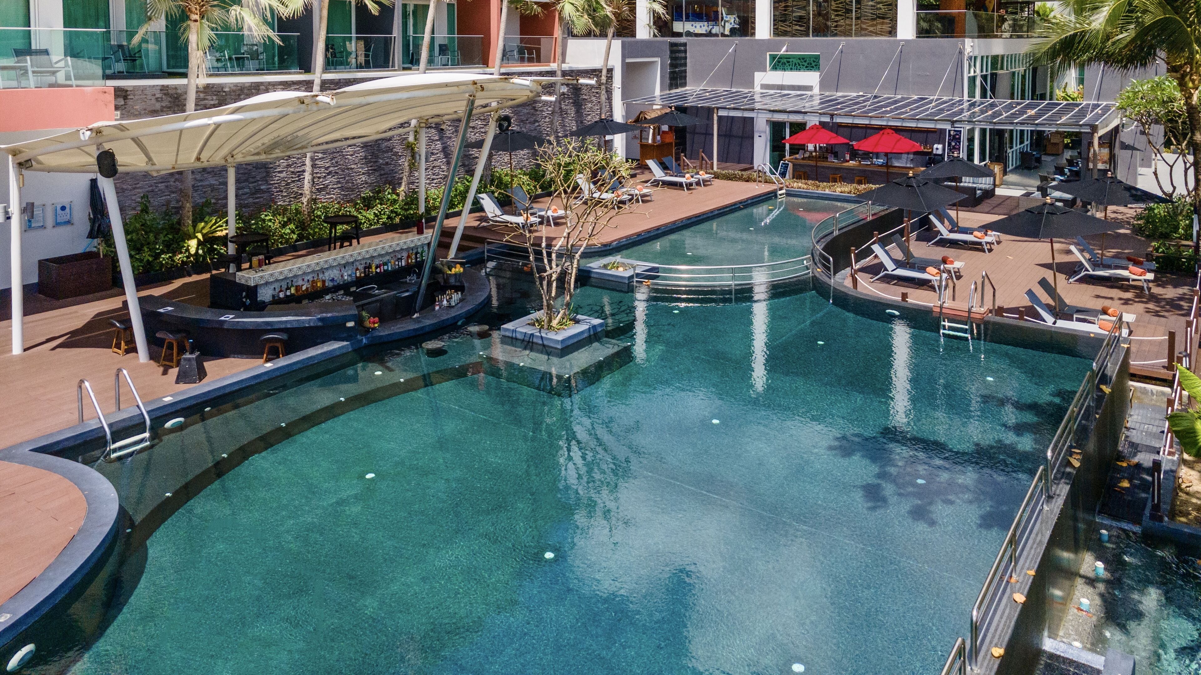 A pool area with lounge chairs, a bar, and a restaurant.