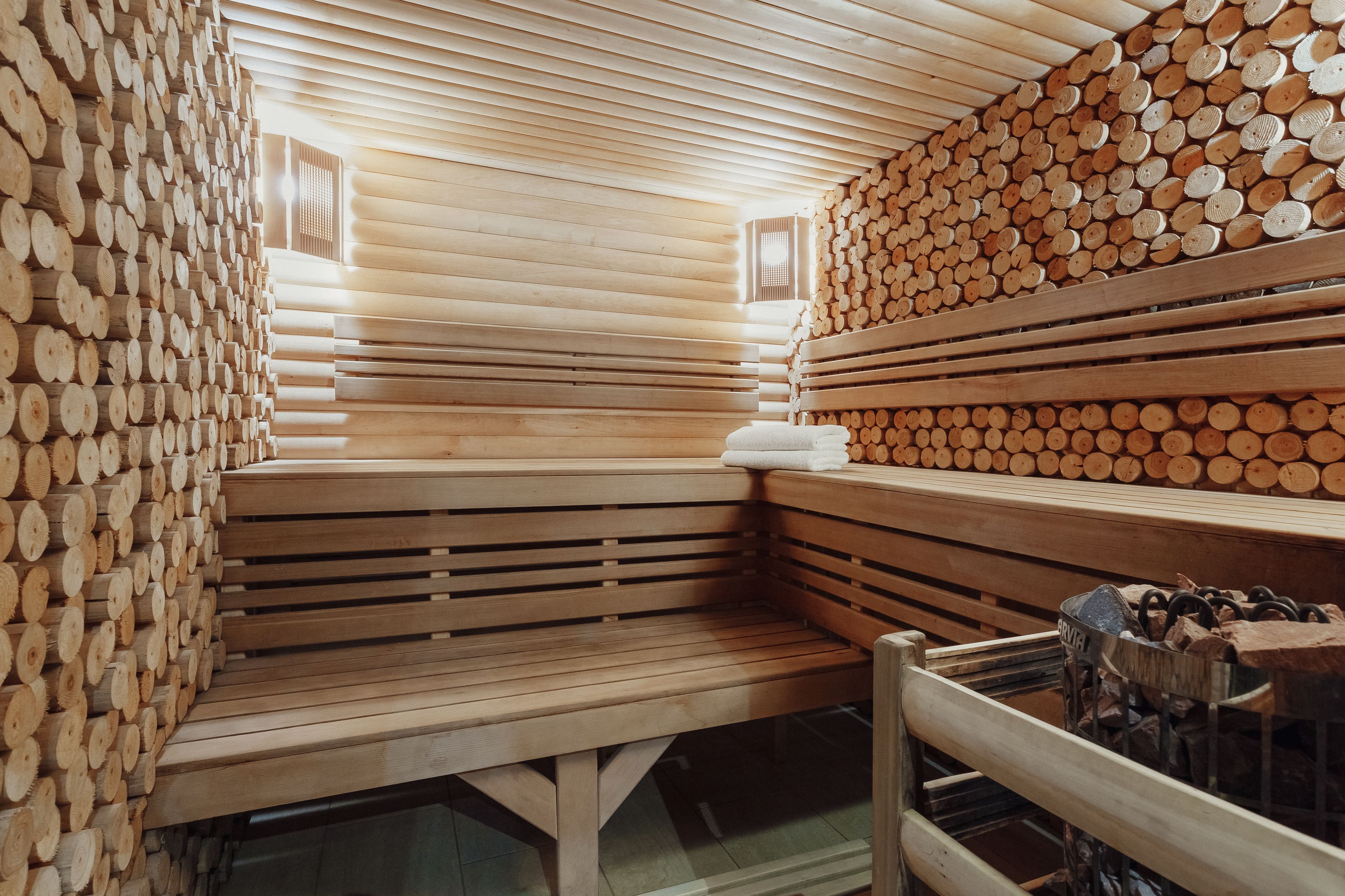 A sauna with wooden benches and walls lined with logs.