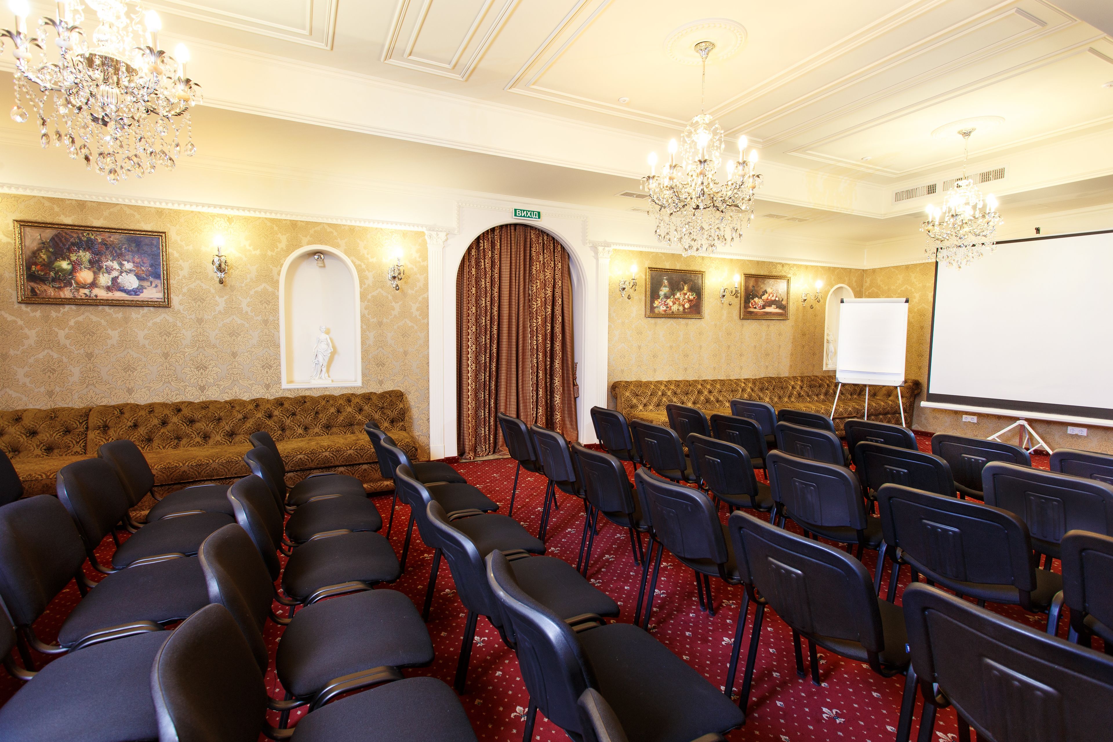 A conference room with rows of chairs, a whiteboard, and a chandelier.