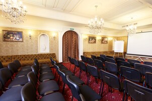 A conference room with rows of chairs, a whiteboard, and a chandelier.