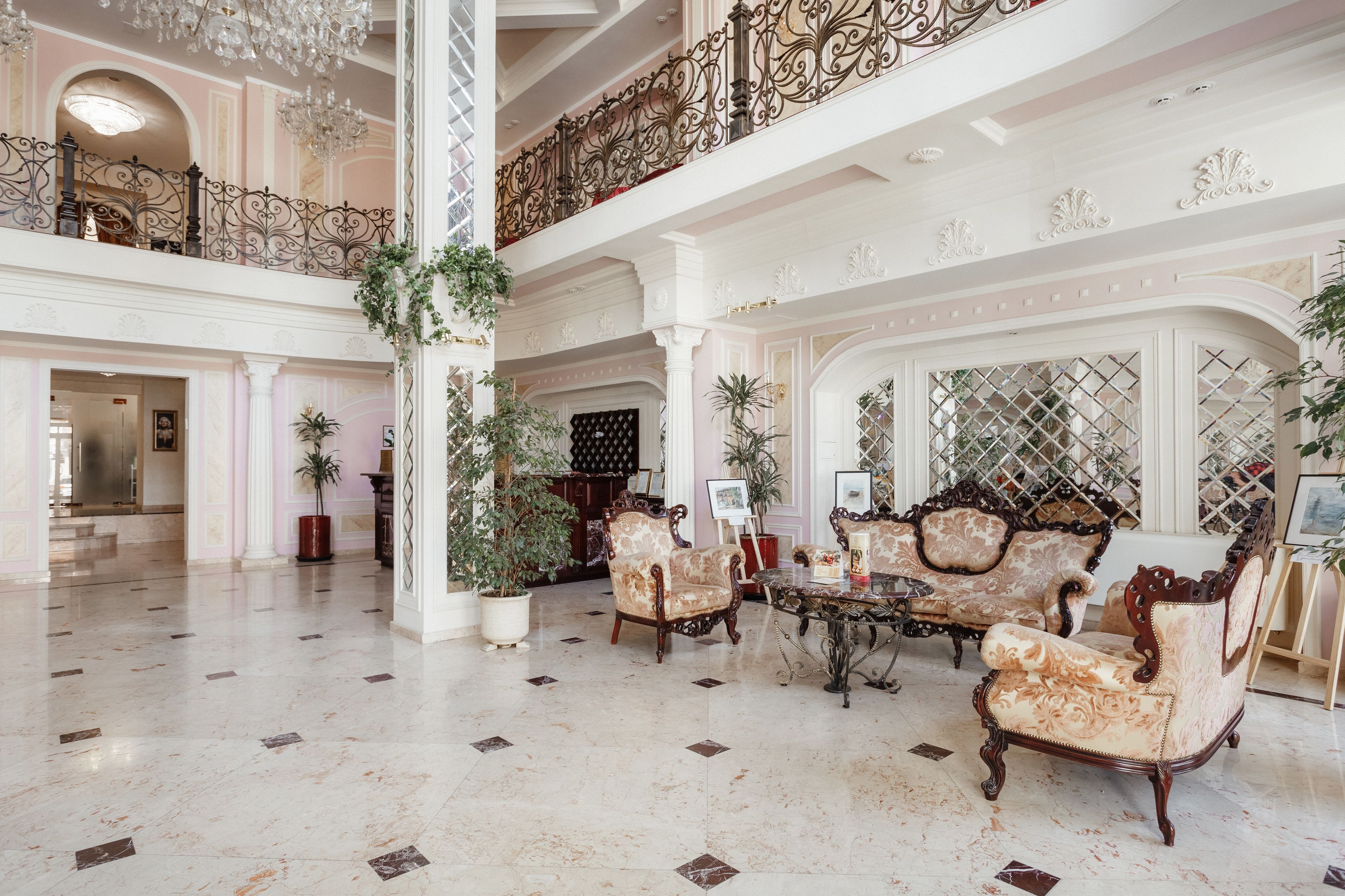 A spacious lobby with ornate furniture, a chandelier, and a high ceiling.