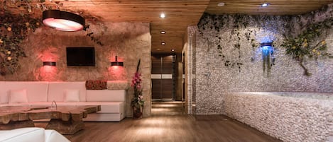 Un interior moderno con techo de madera, paredes de piedra, un sofá blanco, una mesa de centro de madera y una planta en maceta.