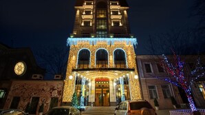 Un hotel de estilo arquitectónico clásico, con una entrada central que destaca por una gran escalera, varios balcones y una fachada decorativa.