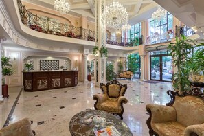 A grand lobby with a marble floor, ornate furniture, and a high ceiling with chandeliers. - California Boutique Hotel (Odesa)