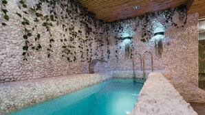 Una piscina interior con pared de guijarros y techo de madera.