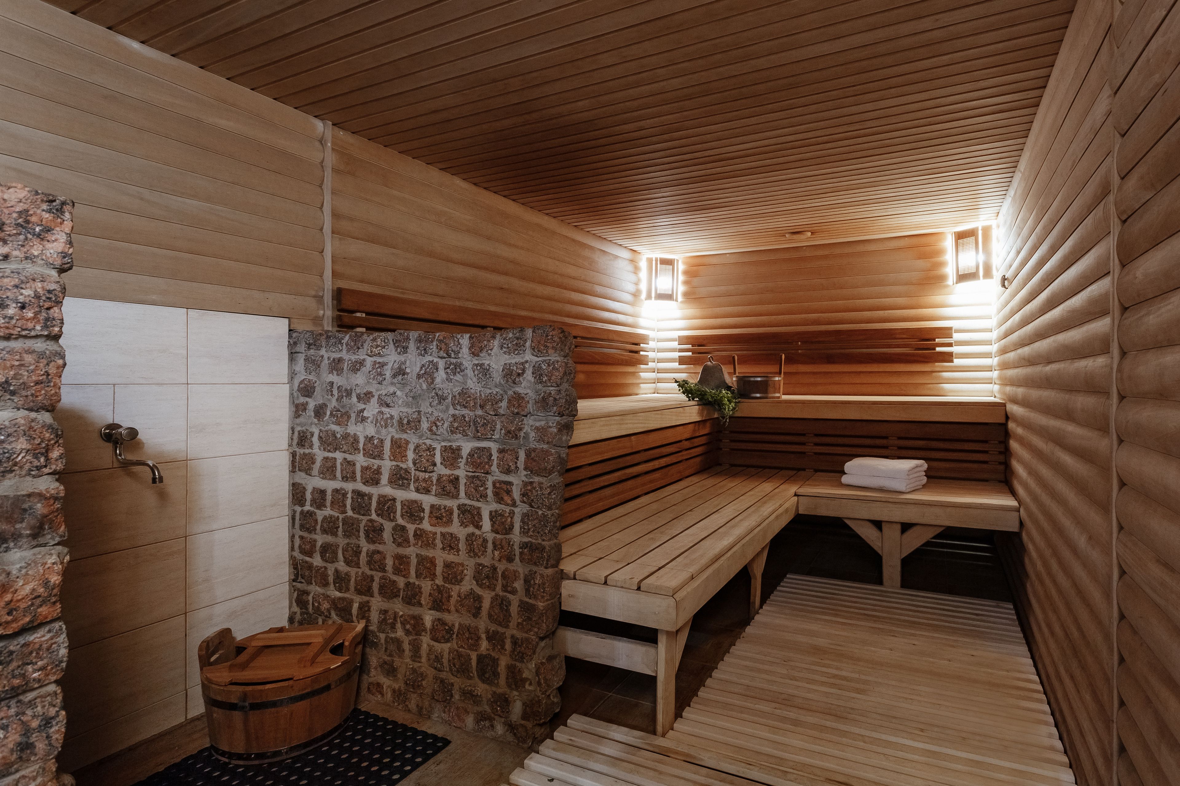 Un sauna avec des bancs en bois, un mur en pierre et un plancher en bois.