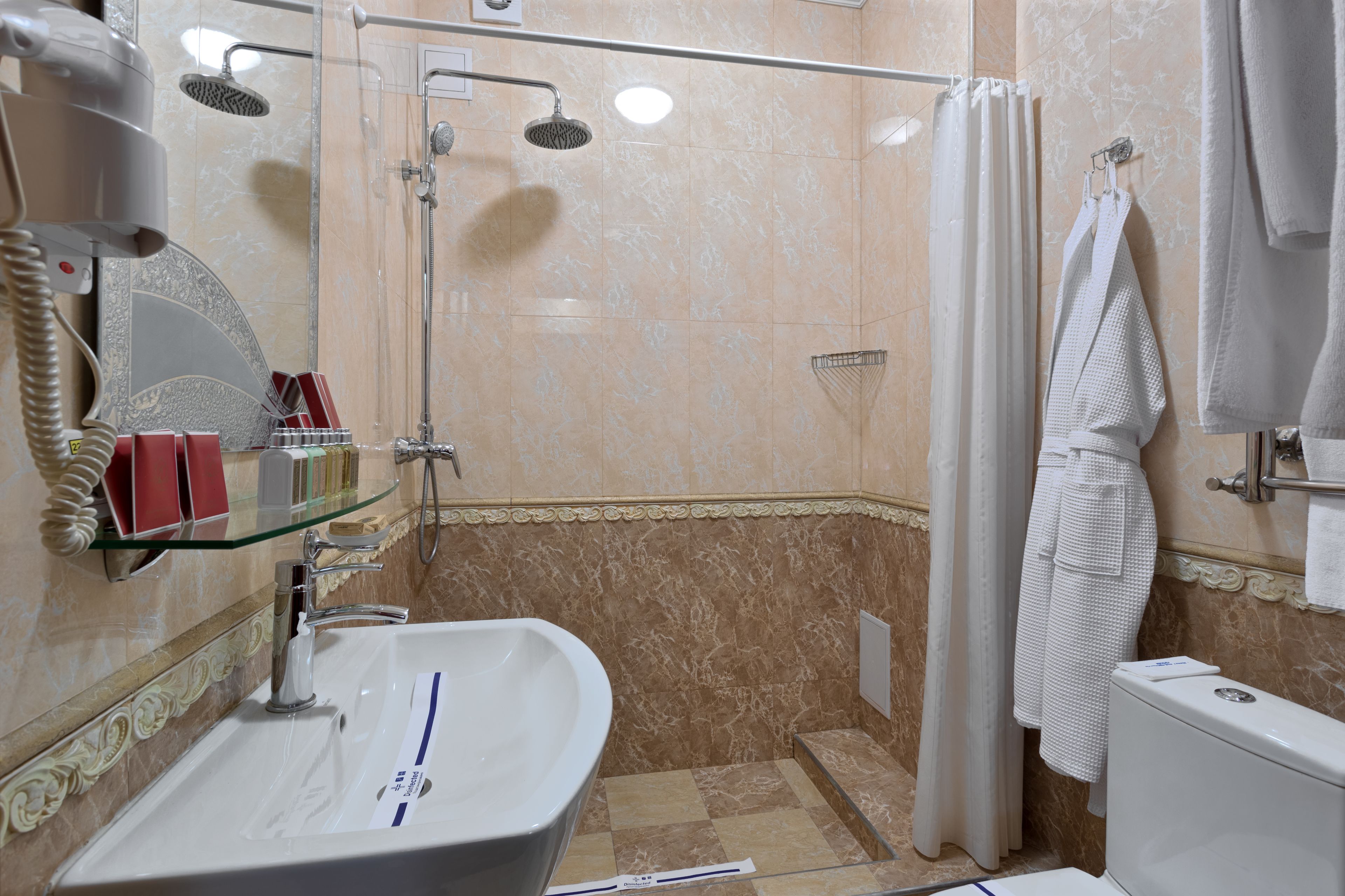 A bathroom with a glass shower enclosure, a sink with a mirror, and a toilet.