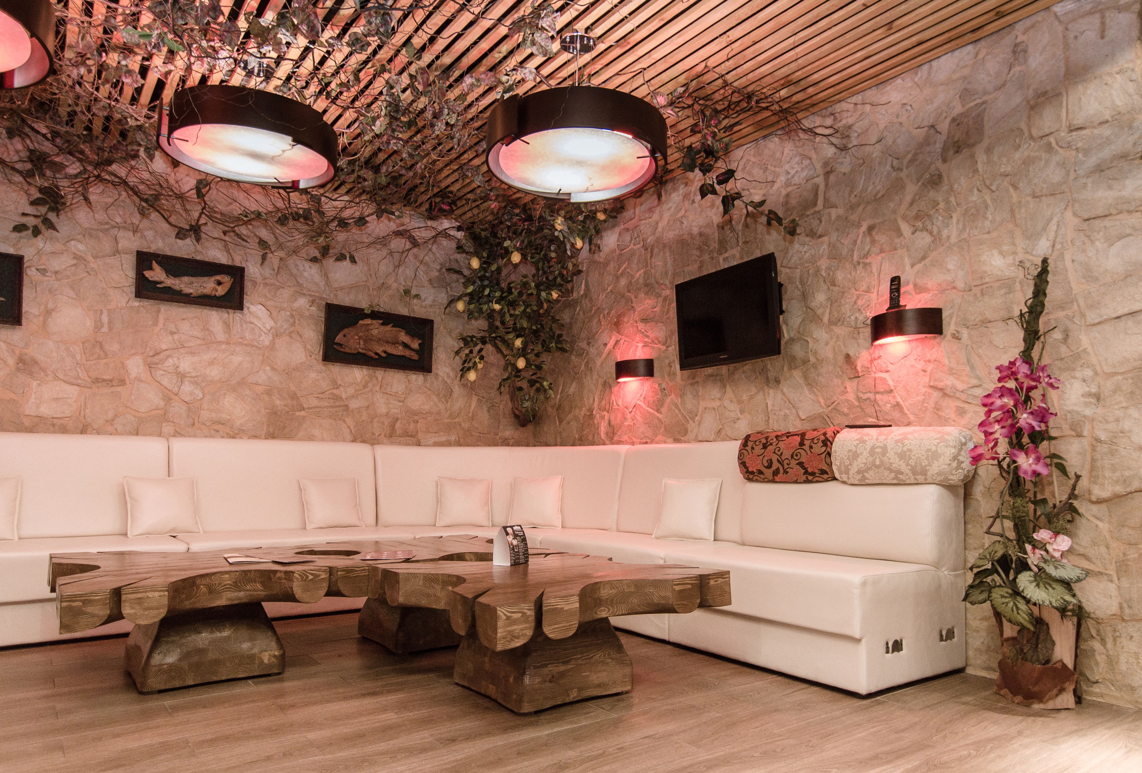 A modern lounge with a stone wall, white sofa, wooden coffee table, and decorative lighting.