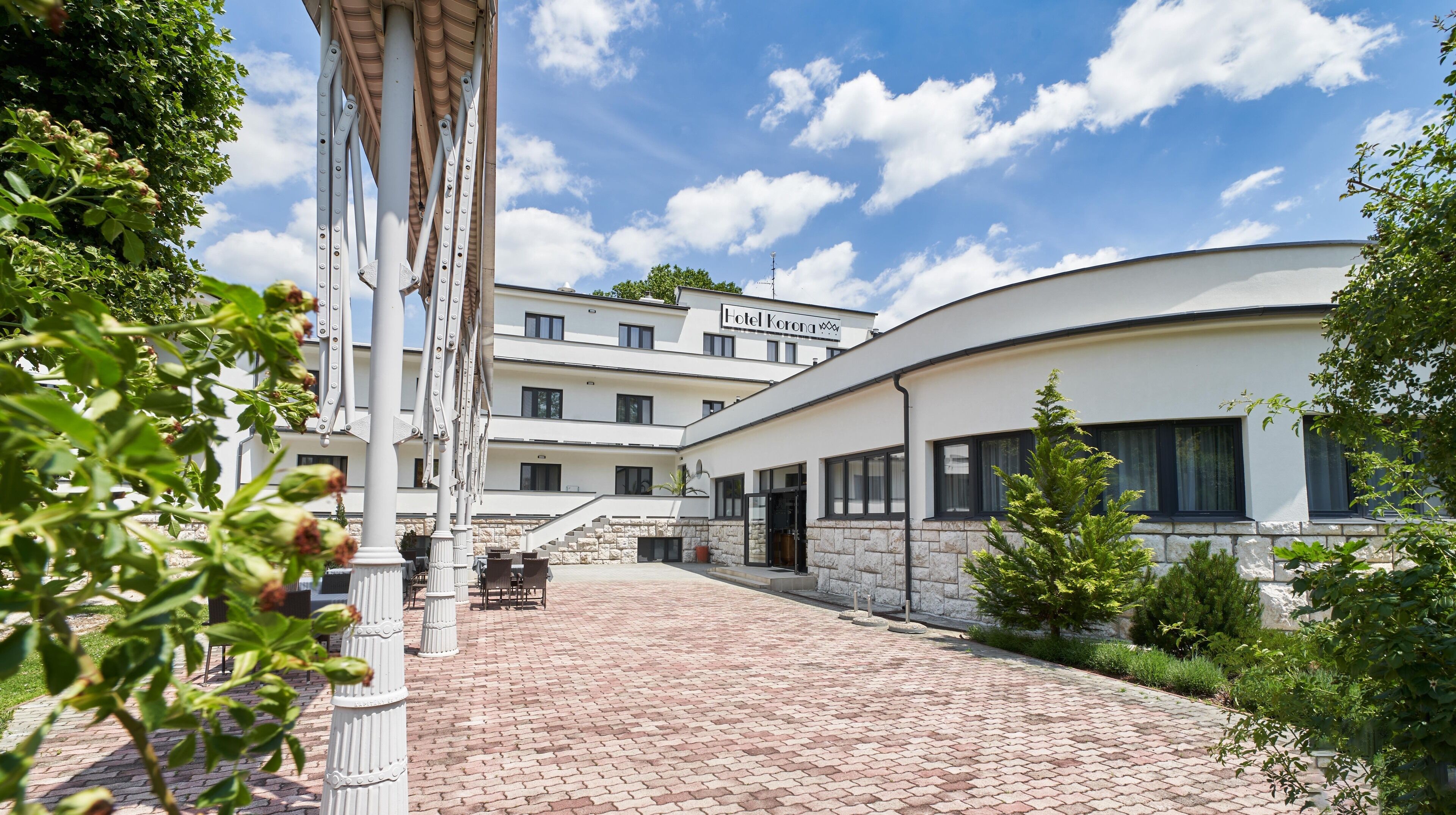 A hotel with a modern design, featuring a courtyard with brick flooring and outdoor seating.