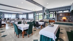 Un amplio comedor con varias mesas y sillas, una recepción y vistas al exterior.
