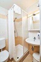 Un baño con ducha, inodoro, lavamanos y espejo.