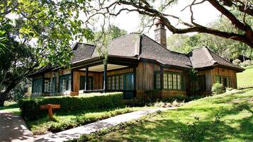 A rustic cabin with a covered porch, surrounded by lush greenery and a well-maintained lawn.