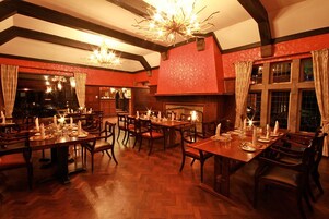 Un restaurante con mesas y sillas de madera, chimenea y candelabros.