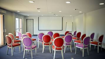 A conference room with rows of chairs, a projector screen, and a whiteboard.