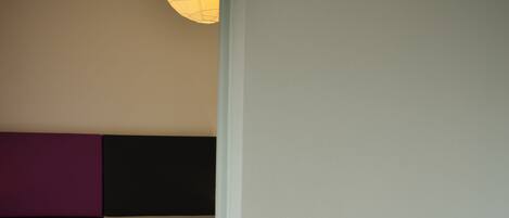 A bedroom with a bed, a chair, and a wall-mounted light fixture.