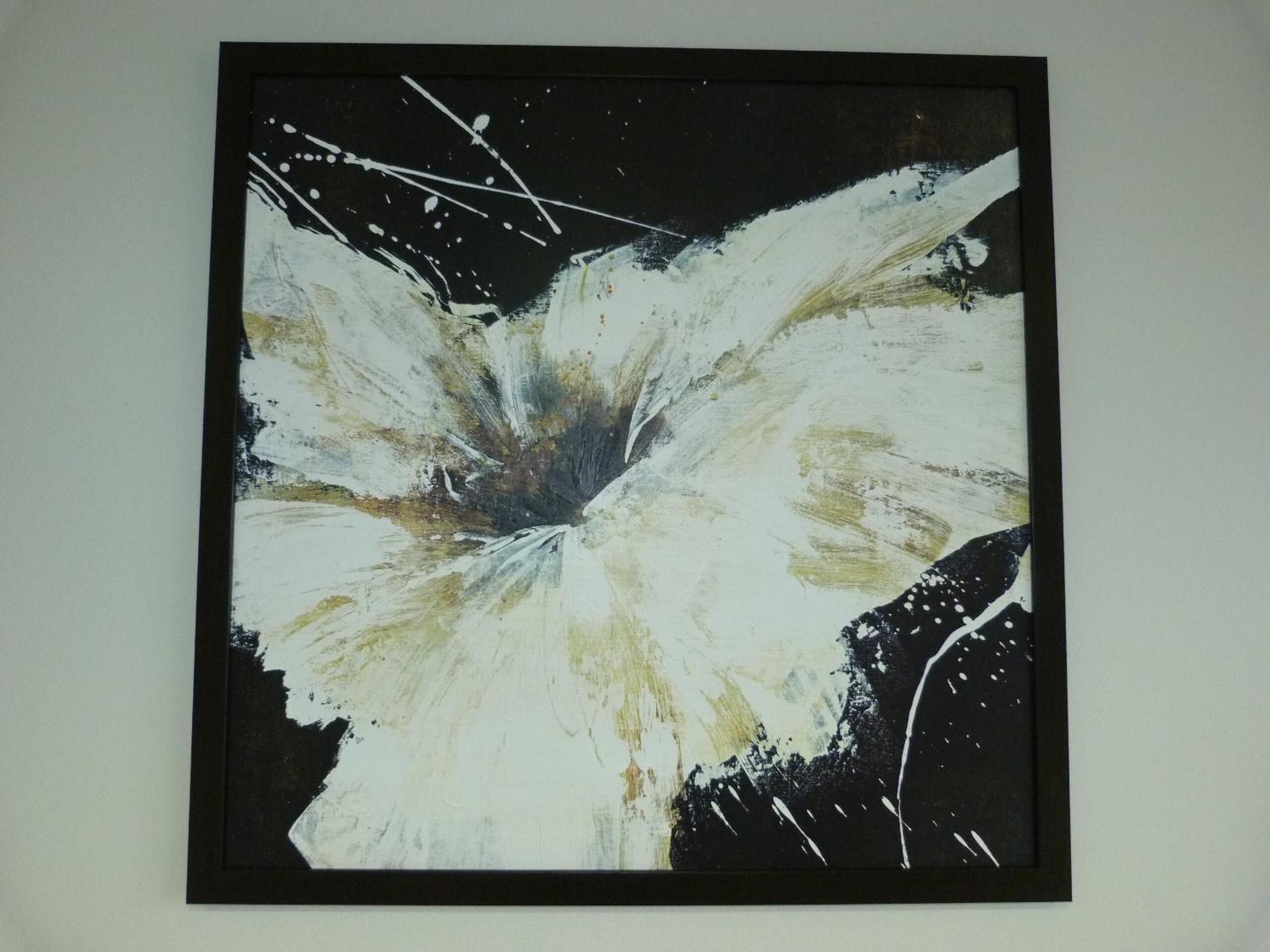 A framed abstract painting with a central burst of white and black colors.