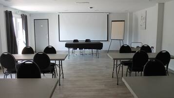 Een vergaderruimte met tafels, stoelen, een projectiescherm en een whiteboard.