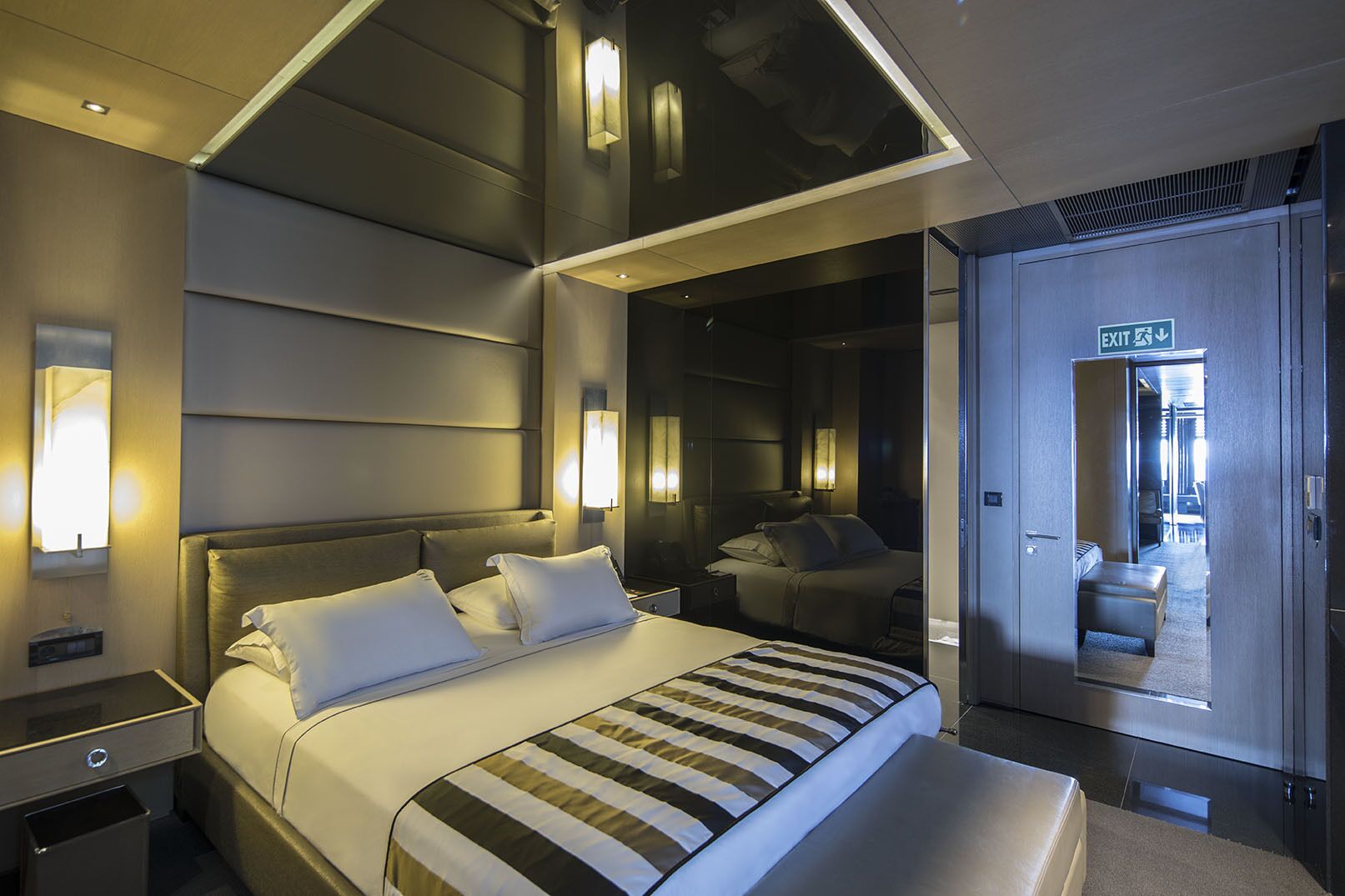 A modern hotel room with a large bed, bedside tables, and a mirror.