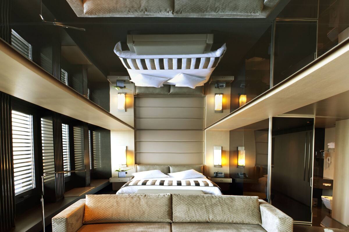 A modern hotel room with a large bed, a sofa, a coffee table, and a view of the city.