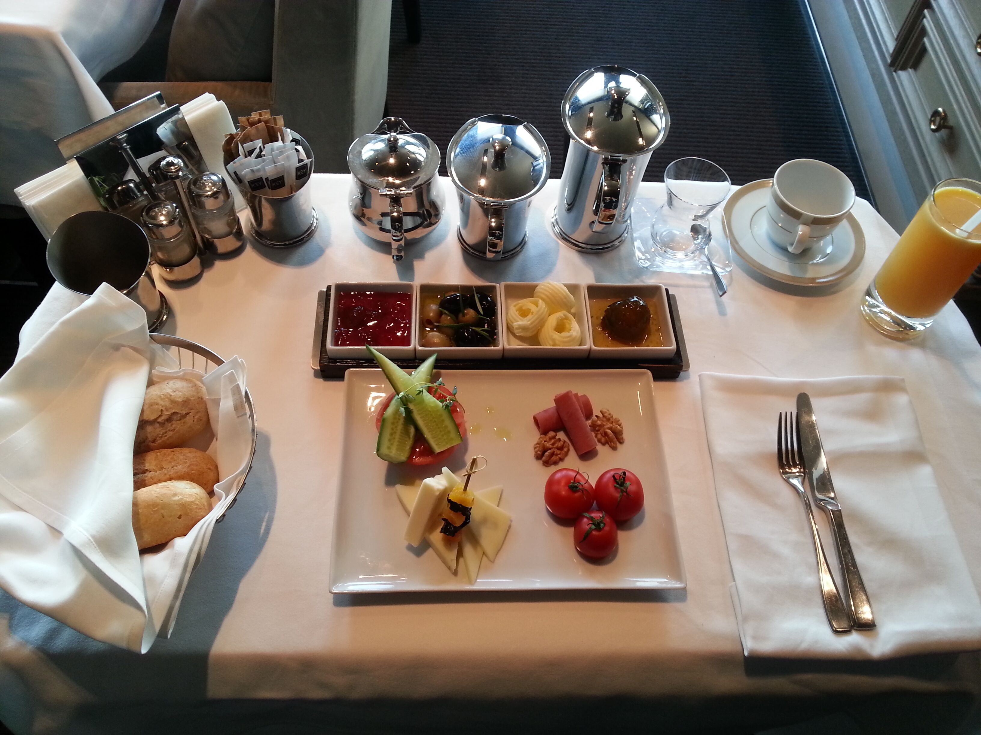 A breakfast table with a variety of food items, including bread, cheese, tomatoes, and condiments.