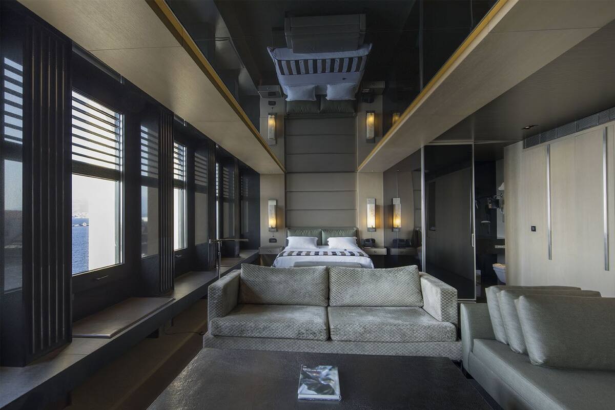 A modern hotel room with a large bed, a sofa, and a coffee table.