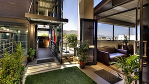 A modern building with a glass entrance, a staircase leading to a balcony, and a seating area with a sofa and a coffee table. - Whale Coast All Suite Hotel (Hermanus)
