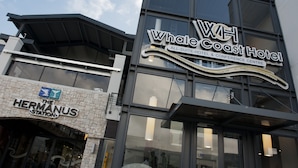 The exterior of the Whale Coast Hotel, featuring a modern architectural design with large windows and a prominent sign. - Whale Coast All Suite Hotel (Hermanus)