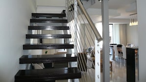 A modern staircase with a metal railing and dark wooden steps leading to an upper floor. - Whale Coast All Suite Hotel (Hermanus)