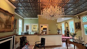 Ein prachtvoller Raum mit einer hohen, verzierten Decke, einem Chandelier, einem Kamin und einem großen, gemusterten Teppich.