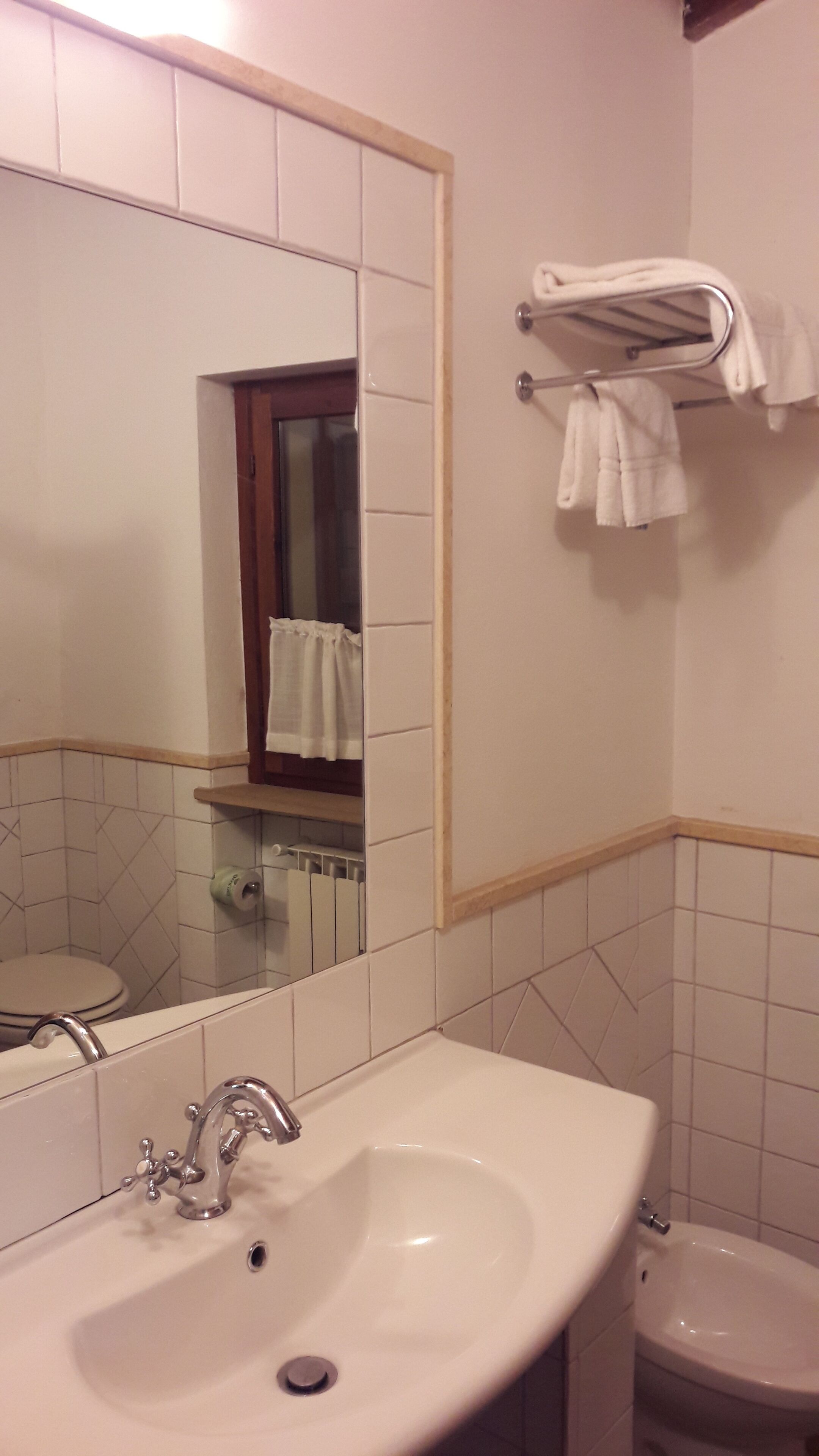 Een badkamer met een wastafel, spiegel en handdoekrek.