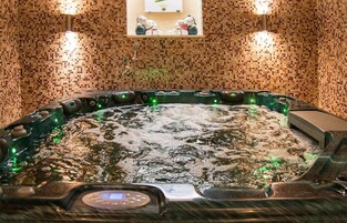 Un jacuzzi con panel de control, rodeado de paredes de mosaicos y dos luces empotradas.