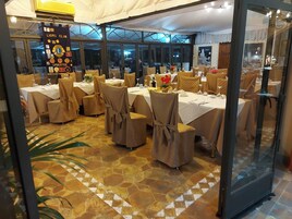 Un restaurante con mesas dispuestas para comer, cubierto por una cubierta de vidrio, y un cartel en la pared.