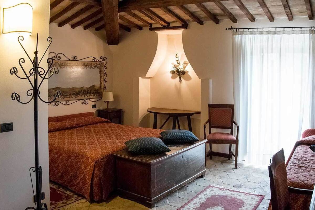 Une chambre confortable avec un lit, une chaise, une table et une lampe.