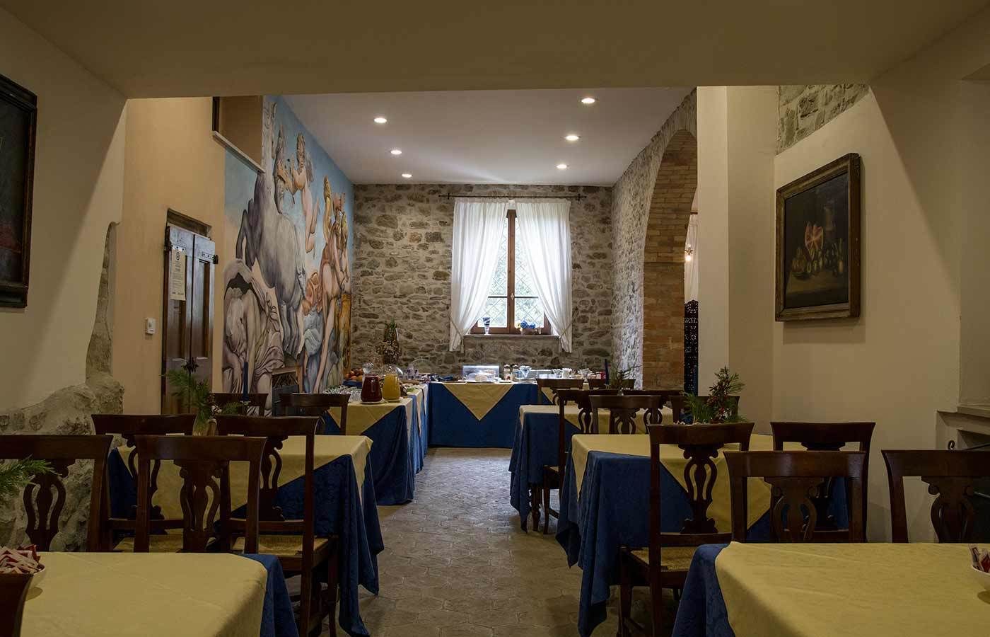 A dining area with stone walls, blue tablecloths, and wooden chairs.