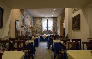 A dining area with stone walls, blue tablecloths, and wooden chairs.