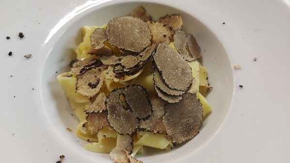 A bowl of pasta with truffle slices.