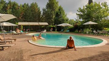 Relax by the serene pool surrounded by lush greenery and comfortable seating options.