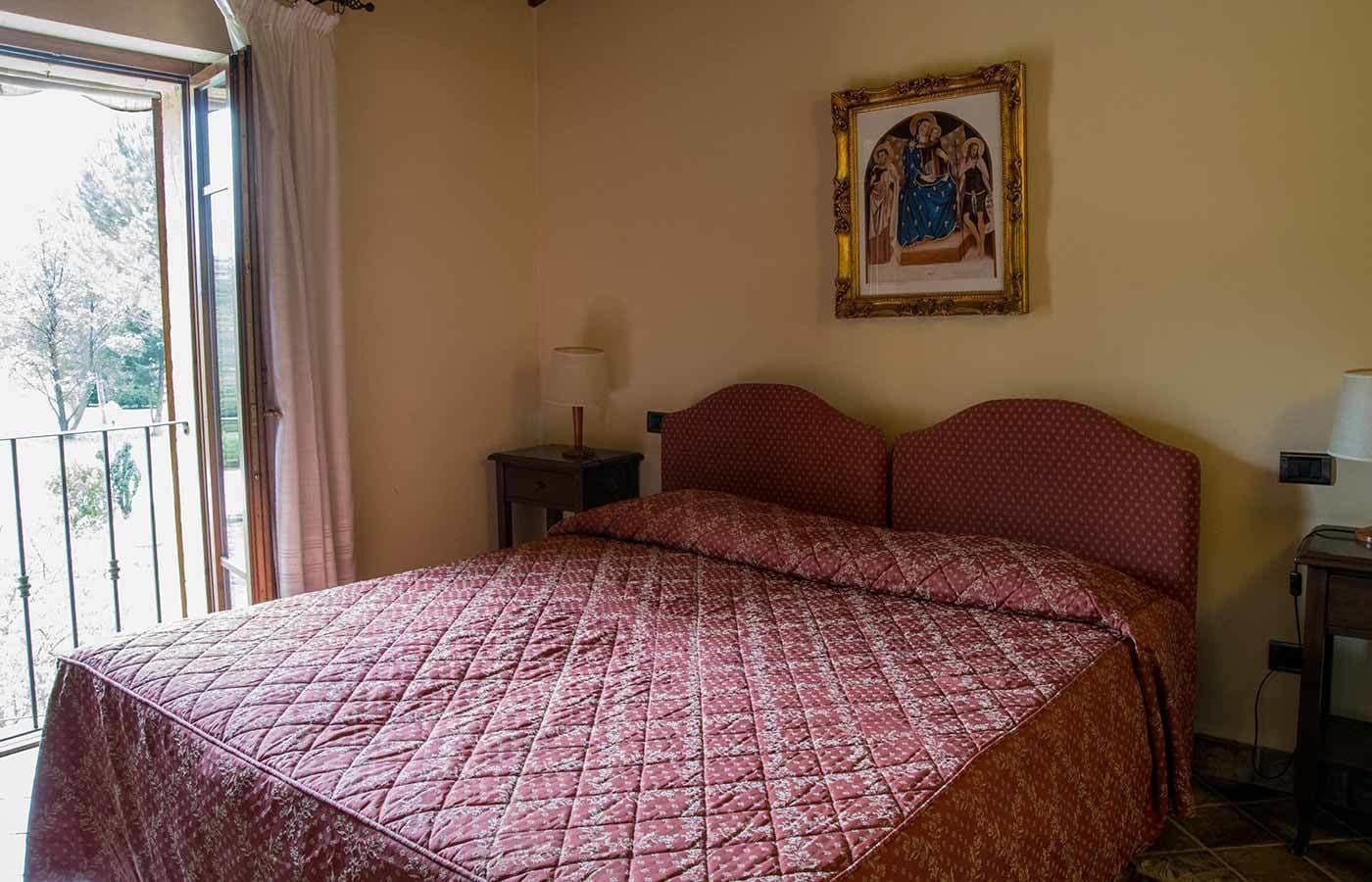 A bedroom with a large bed, a nightstand, a lamp, and a framed picture on the wall.