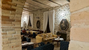 Une pièce avec un mur en pierre, un coin repas avec une table et des chaises, et un canapé.