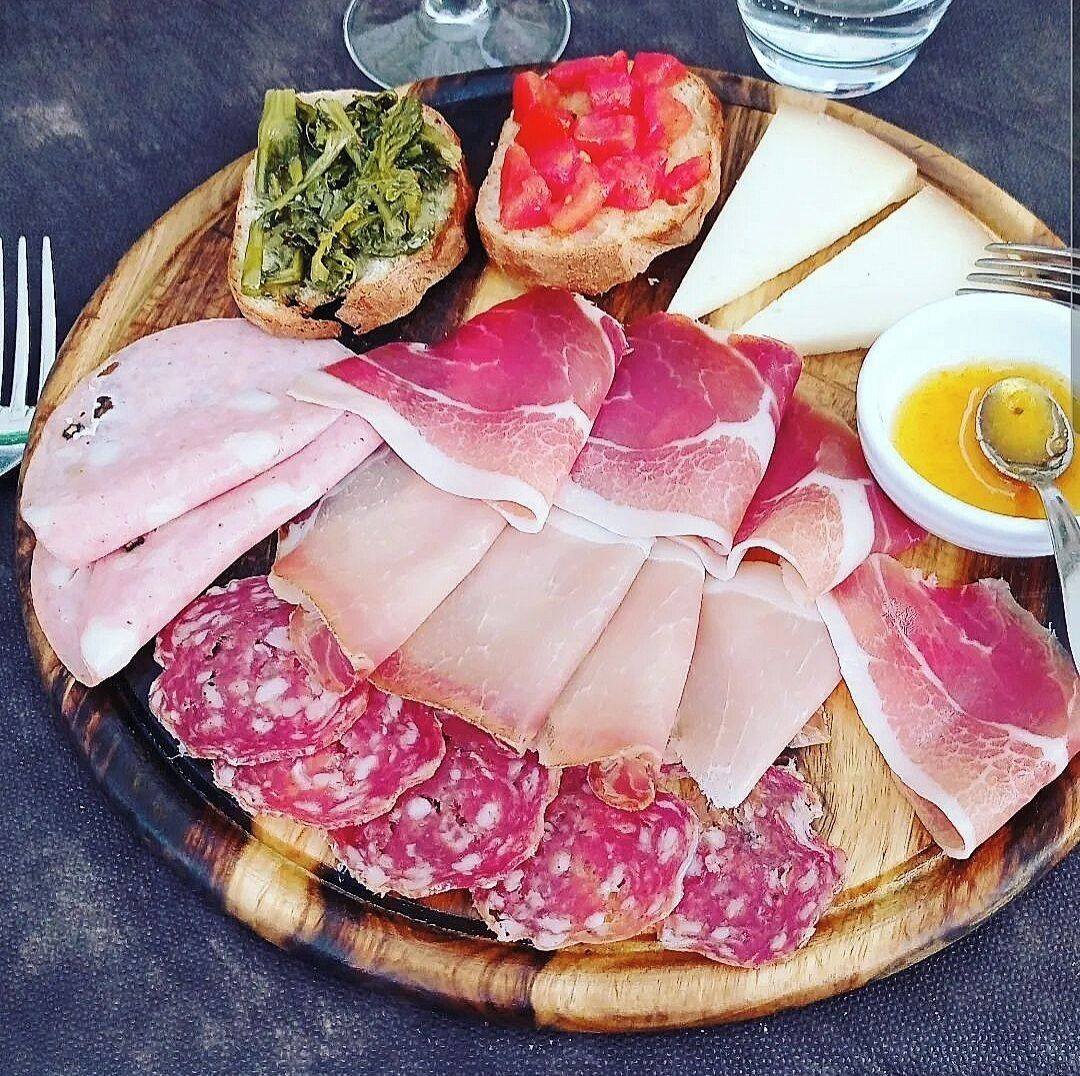 Une planche de charcuterie avec différentes sortes de viandes, de fromages et de pain.