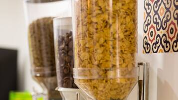 A cereal dispenser with multiple containers and a metal bowl in front.