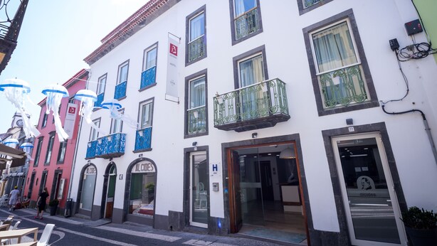 A hotel with a white facade, multiple balconies, and a visible entrance.