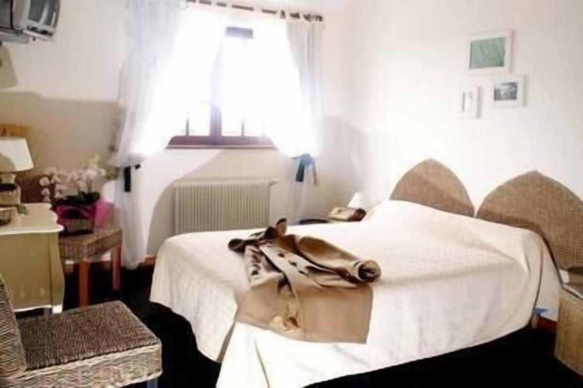 A hotel room with a bed, a desk, a chair, and a radiator.