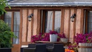 A wooden cabin with a patio area featuring outdoor seating and potted plants.